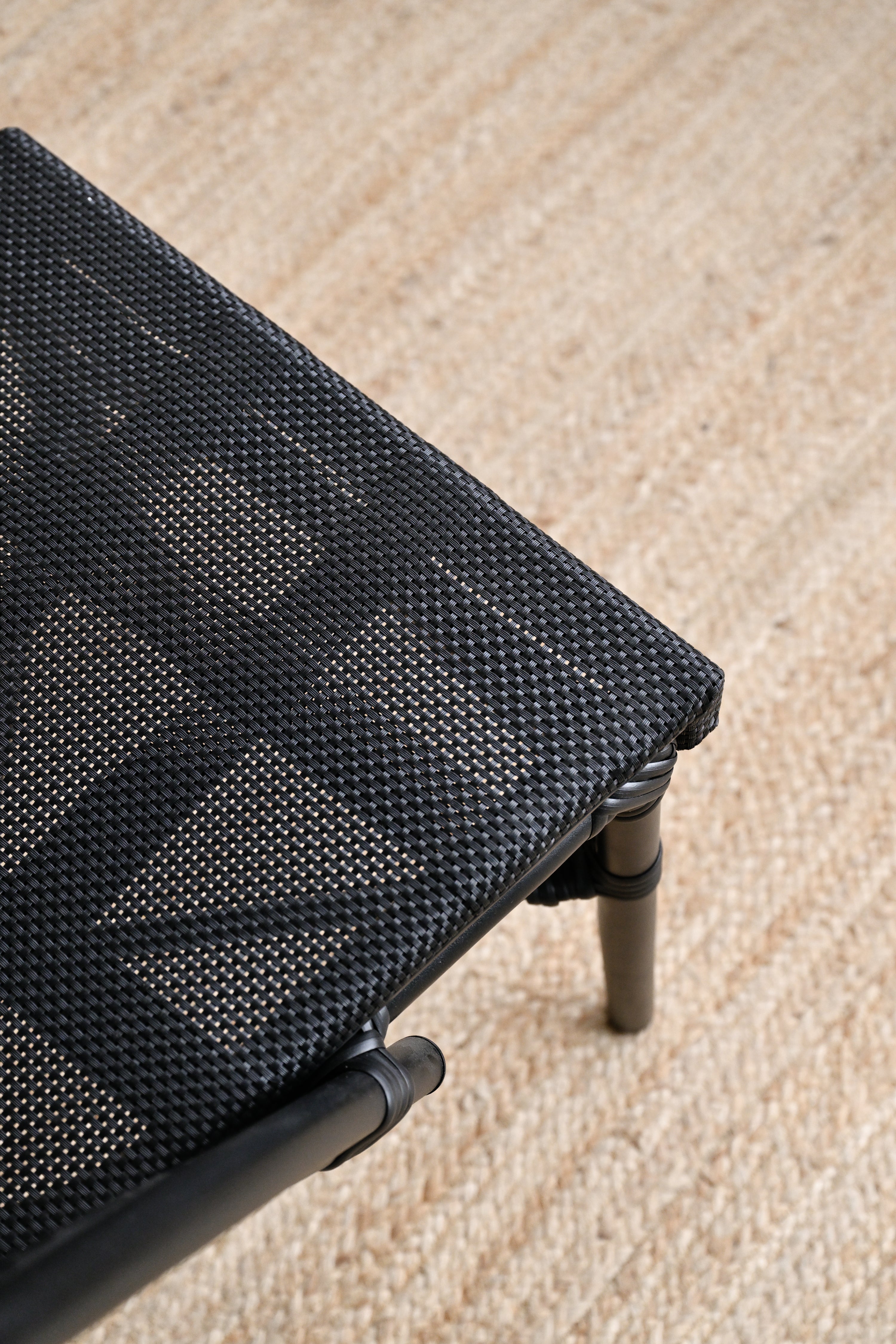 Close-up of a black woven chair on a beige carpet