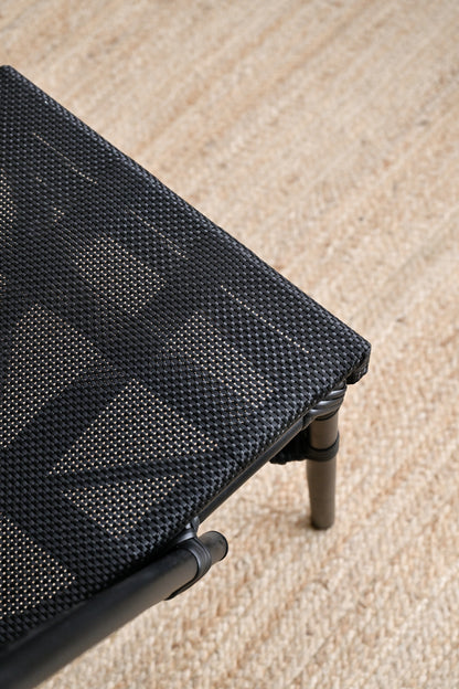 Close-up of a black woven chair on a beige carpet