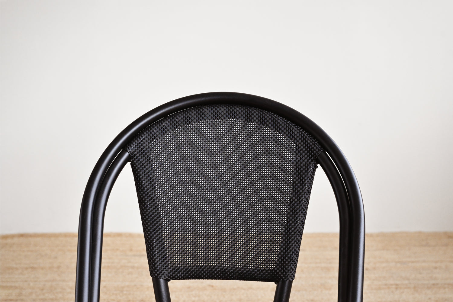 Black metal chair with a textured backrest on a wooden floor.