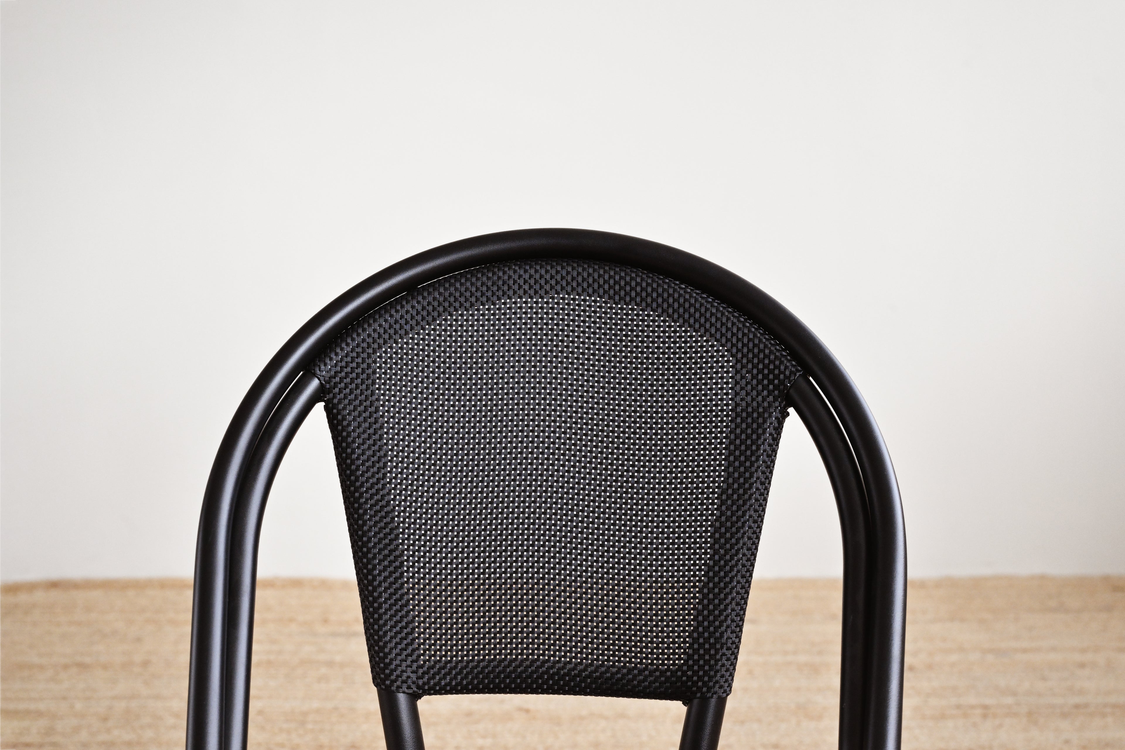 Black metal chair with a textured backrest on a wooden floor.