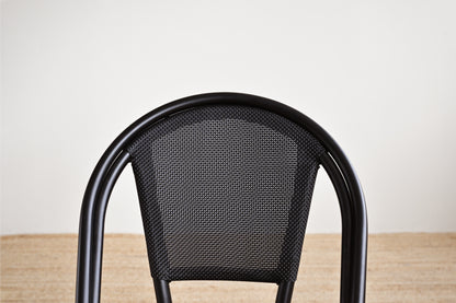 Black metal chair with a textured backrest on a wooden floor.