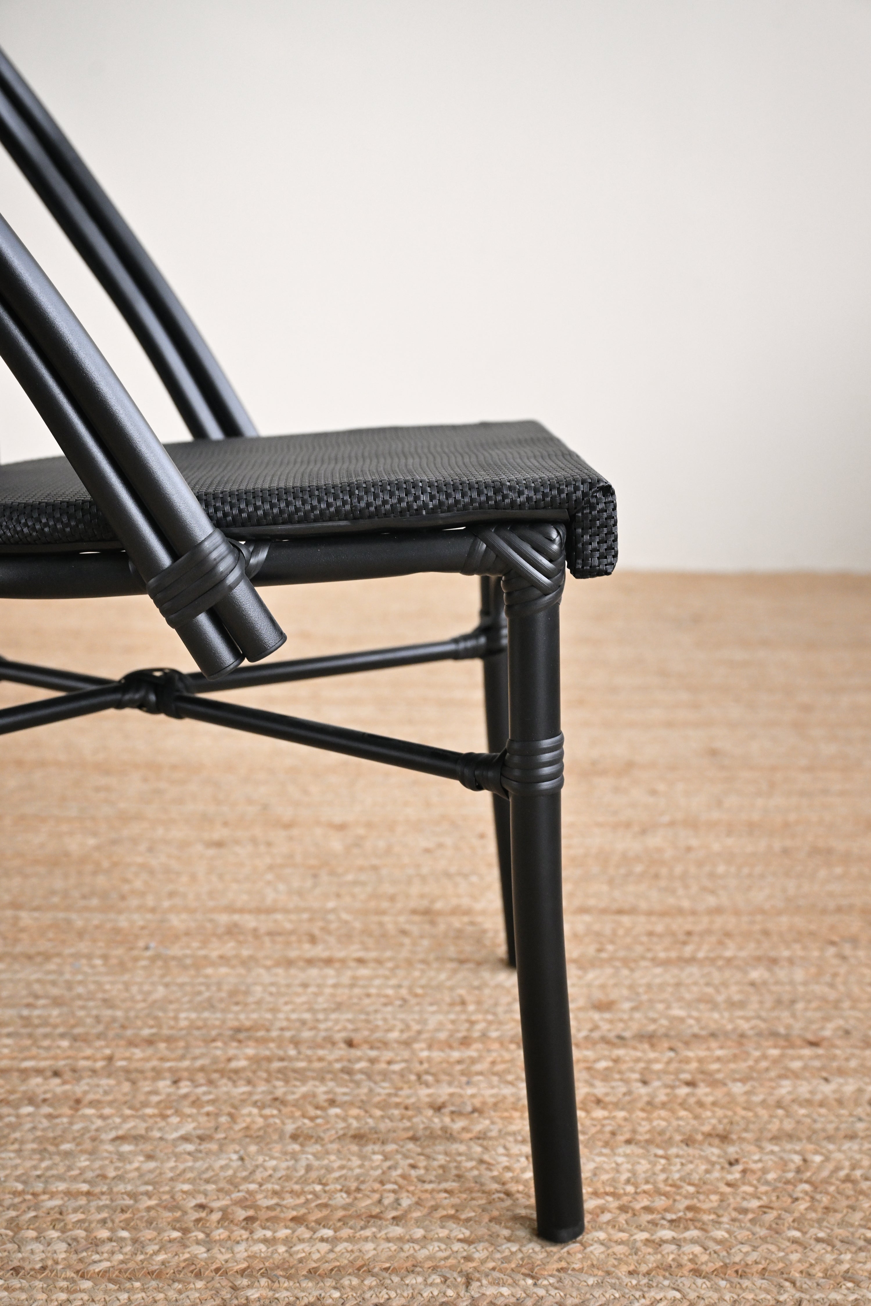 Black metal chair with woven seat on a beige carpet
