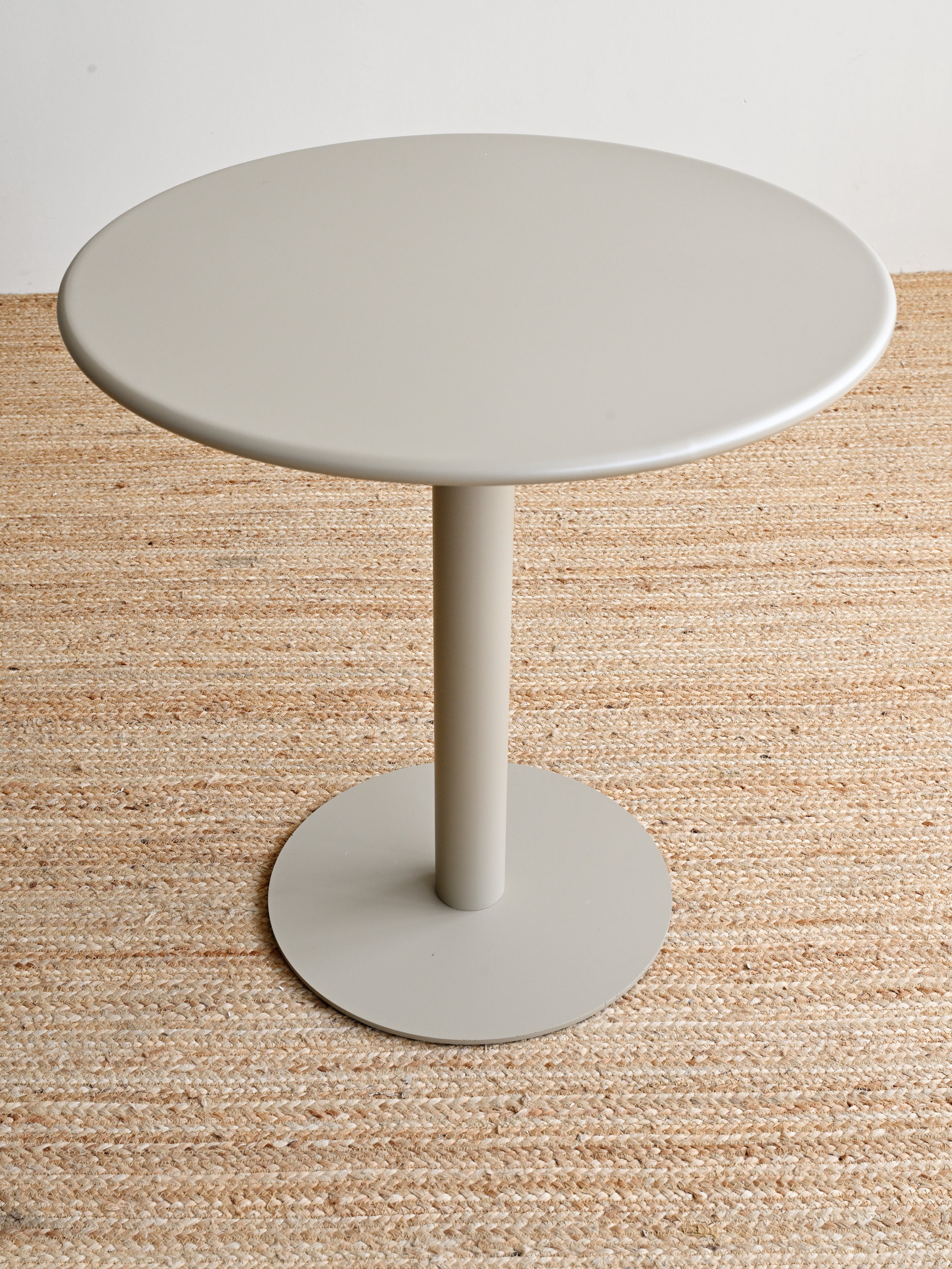 Round gray side table on a textured beige surface