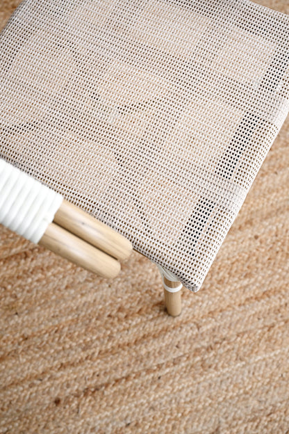 Close-up of a textured white screen or curtain on a wooden stool against a brown carpeted floor.