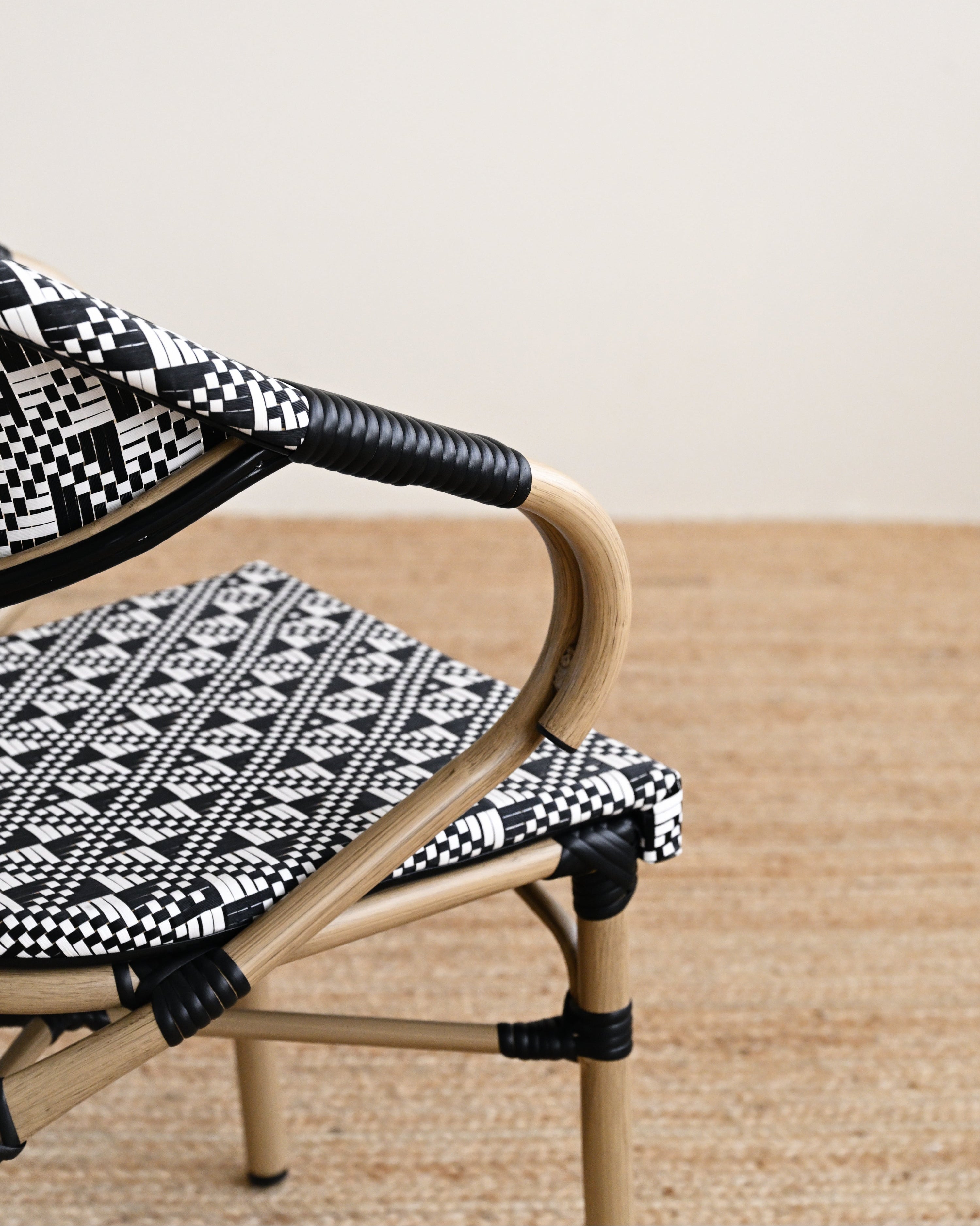 Wicker chair with black and white patterned cushions on a wooden floor.