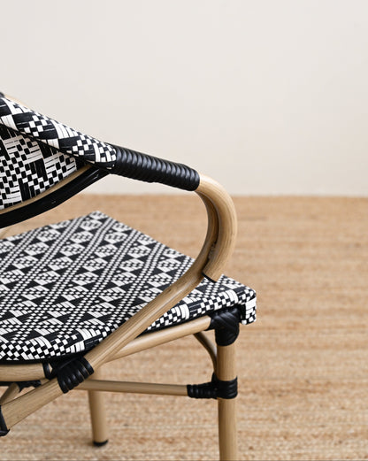 Wicker chair with black and white patterned cushions on a wooden floor.
