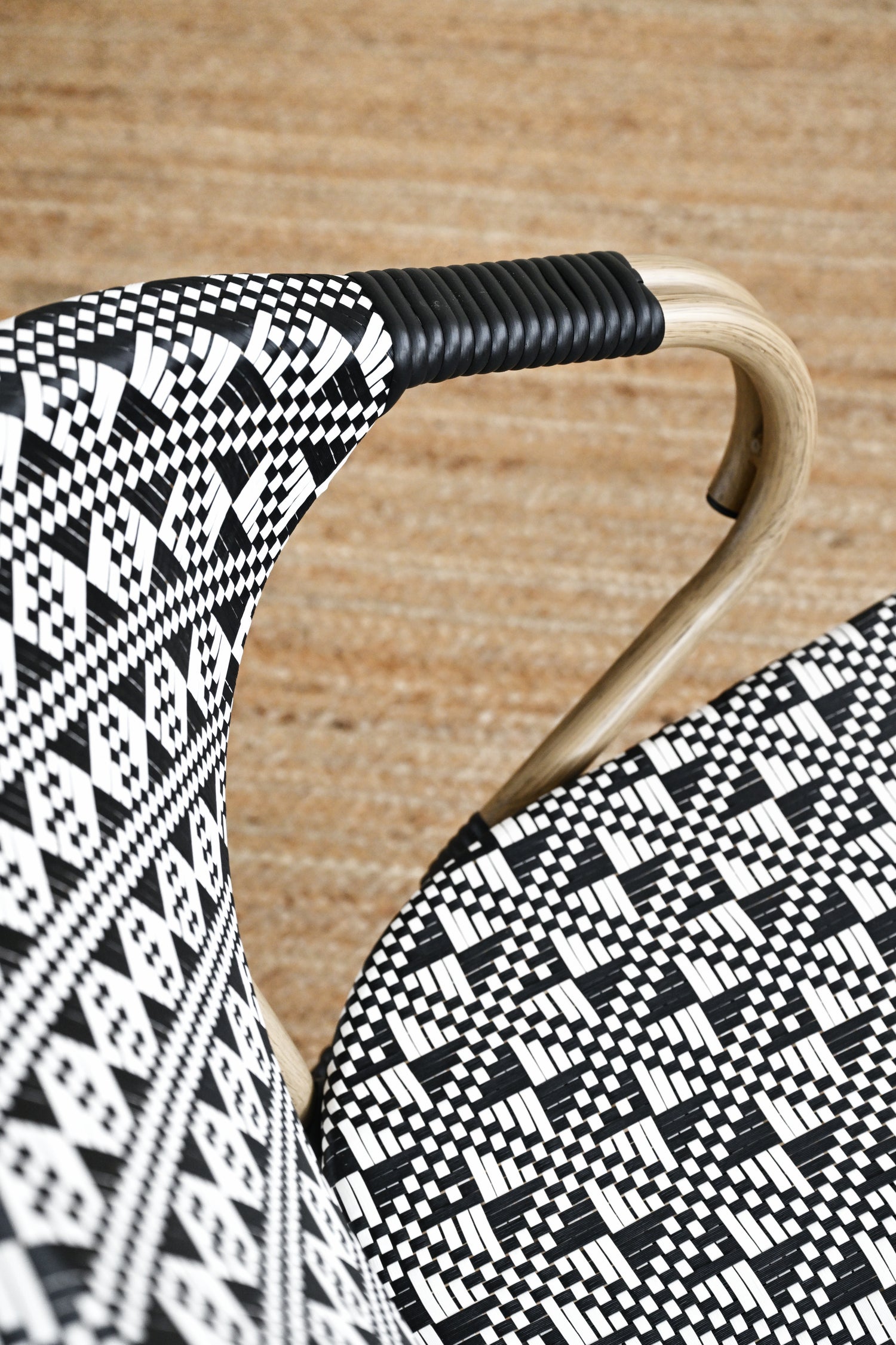 Close-up of a chair with black and white patterned seat and backrest on a wooden floor.
