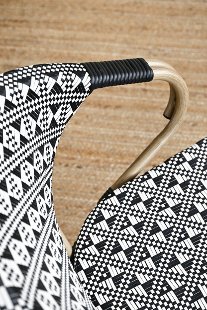 Close-up of a chair with black and white patterned seat and backrest on a wooden floor.