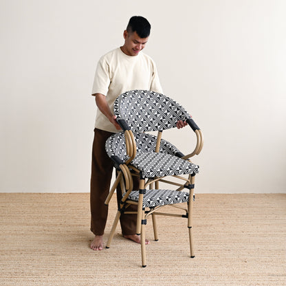 Person arranging patterned chairs on a wooden floor with a white wall background