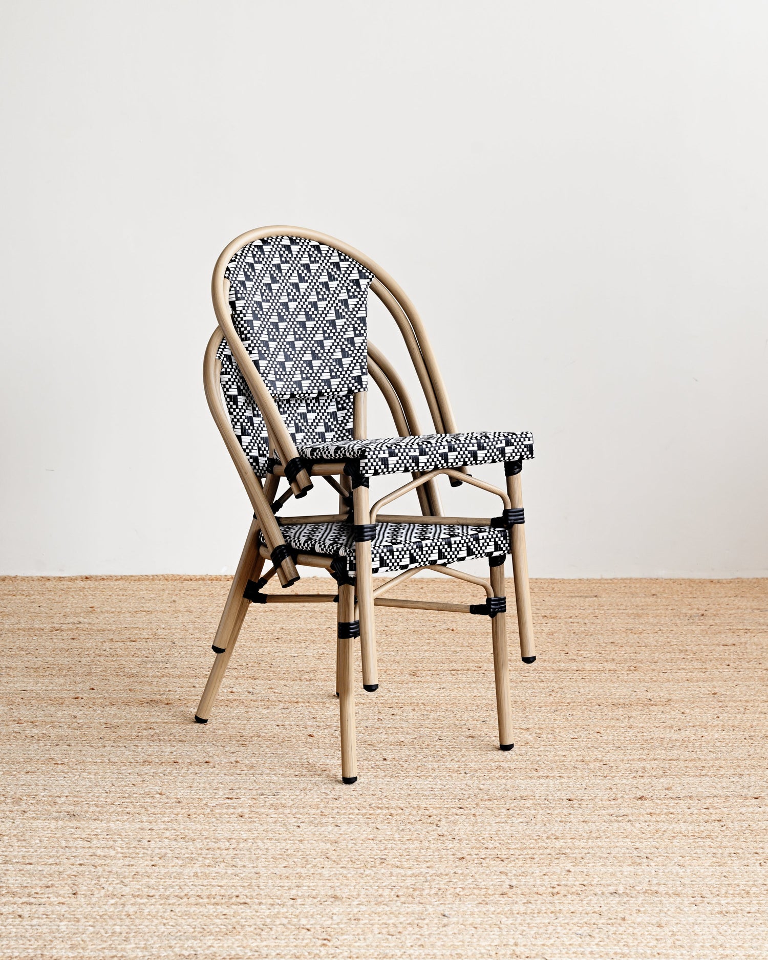 Chair with patterned backrest and seat on a wooden floor with a white wall background