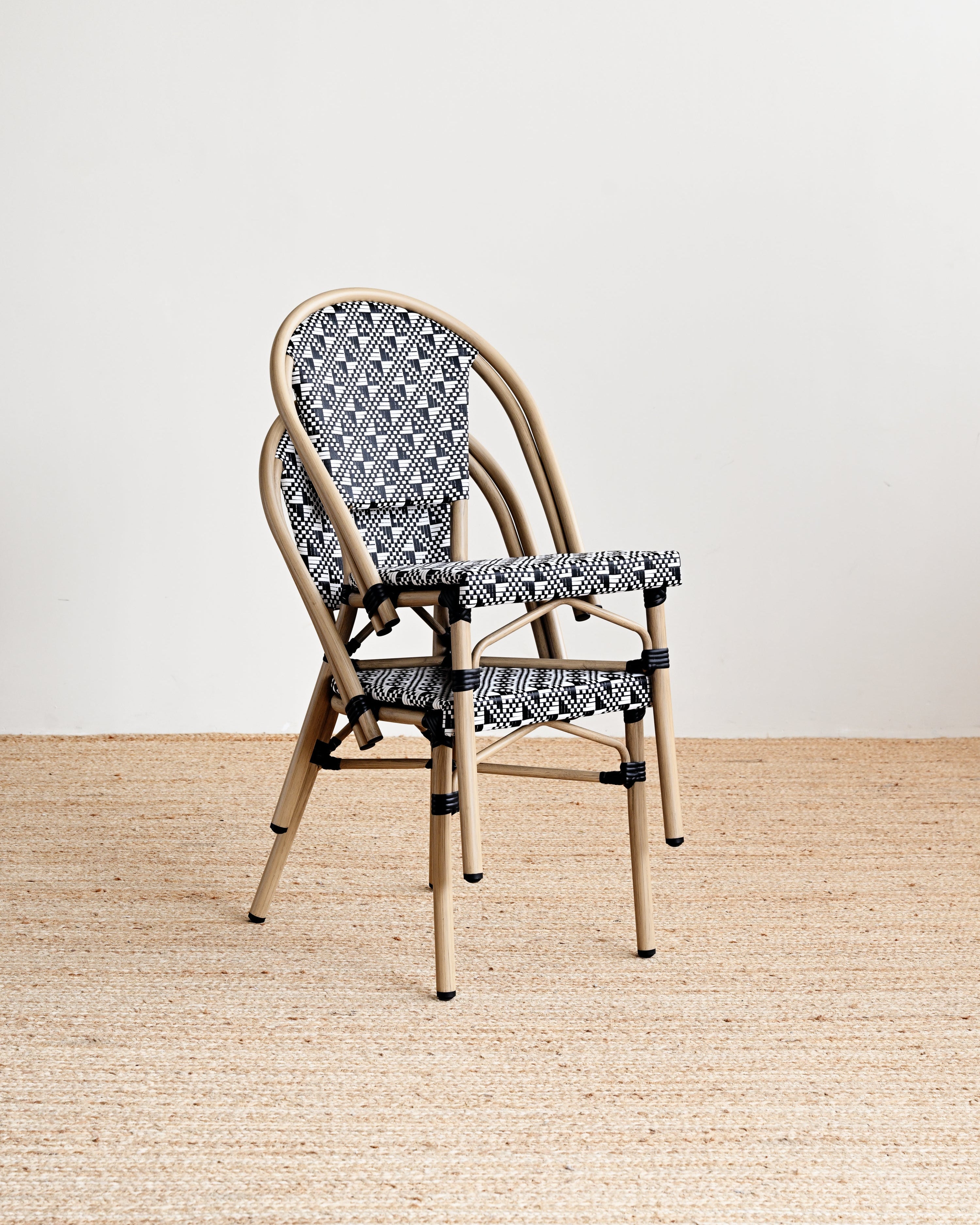 Chair with patterned backrest and seat on a wooden floor with a white wall background