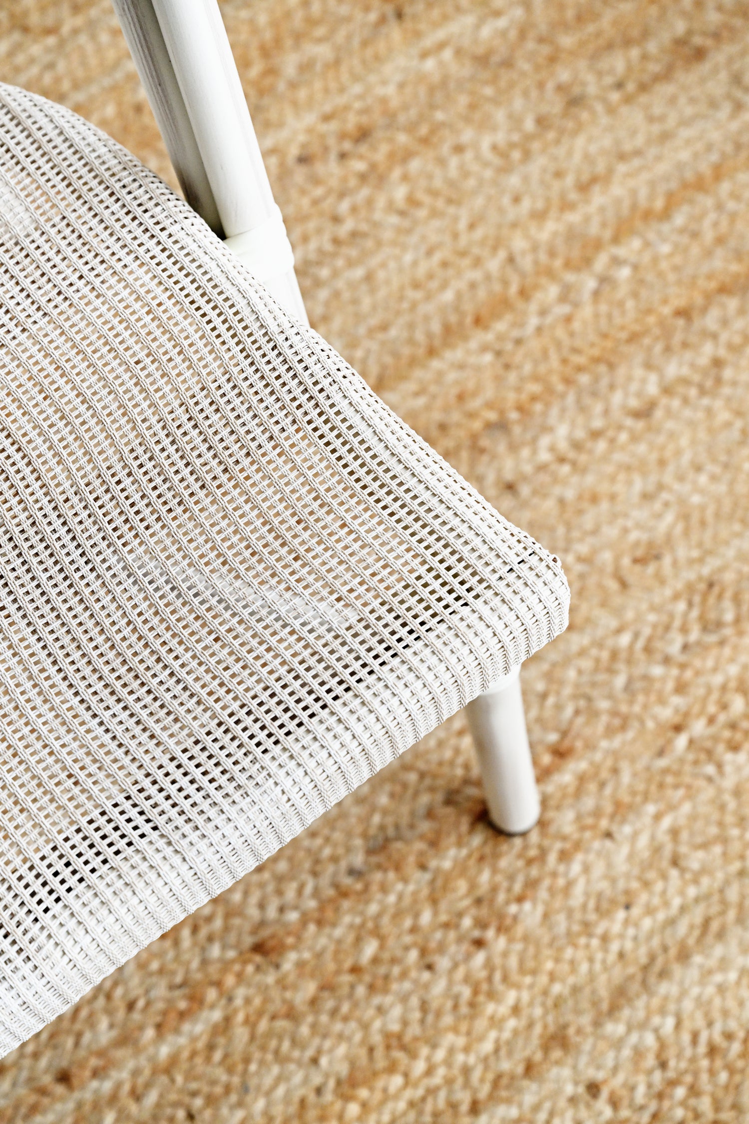 Close-up of a white wicker chair on a textured beige surface
