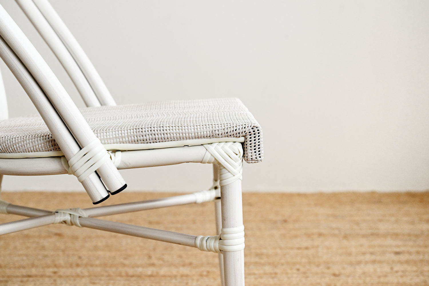 White wicker chair with a textured cushion on a wooden floor.