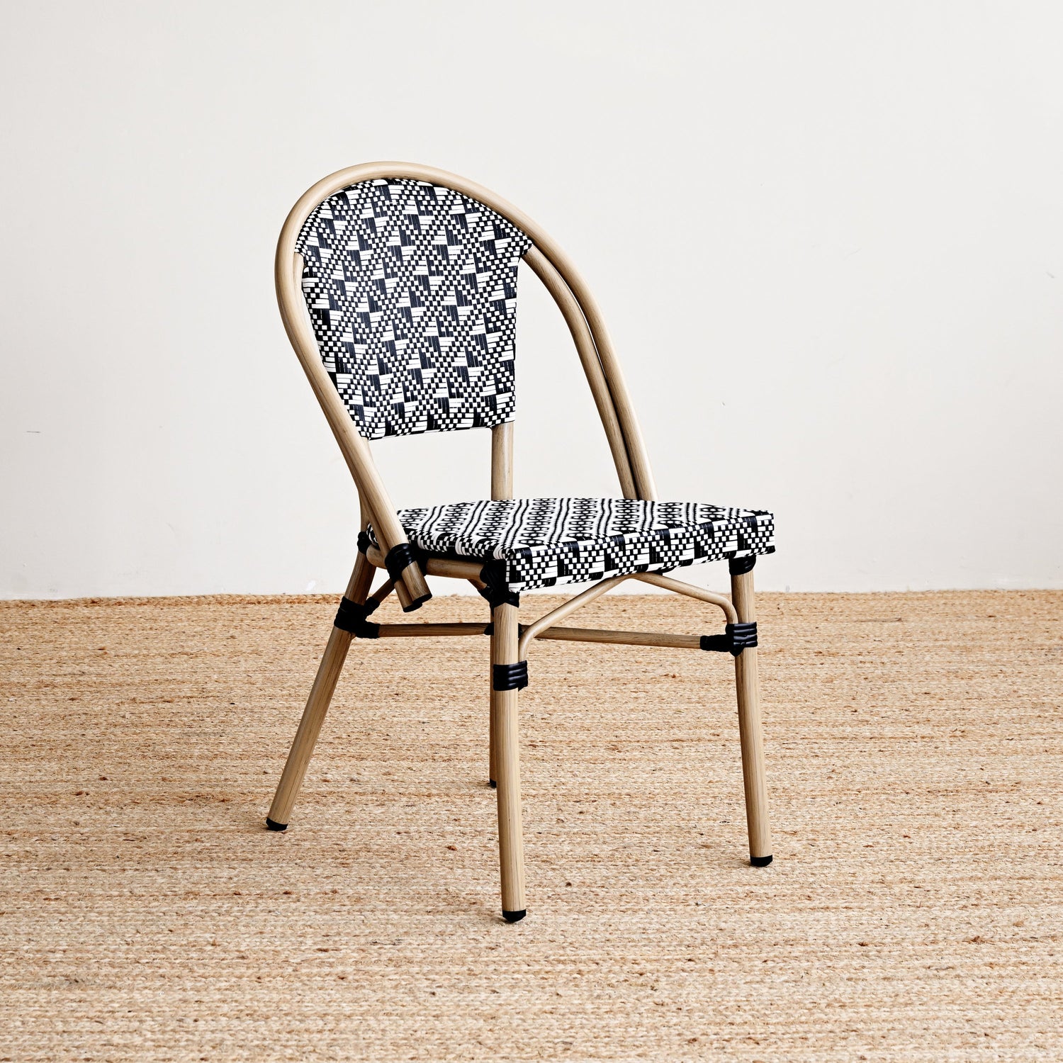 Chair with patterned backrest and seat on a beige floor and white wall background