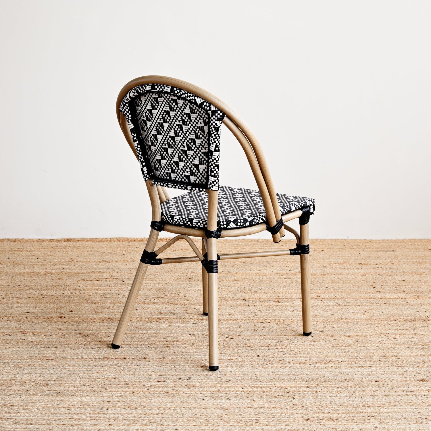 Chair with woven backrest and patterned cushion on a beige floor.