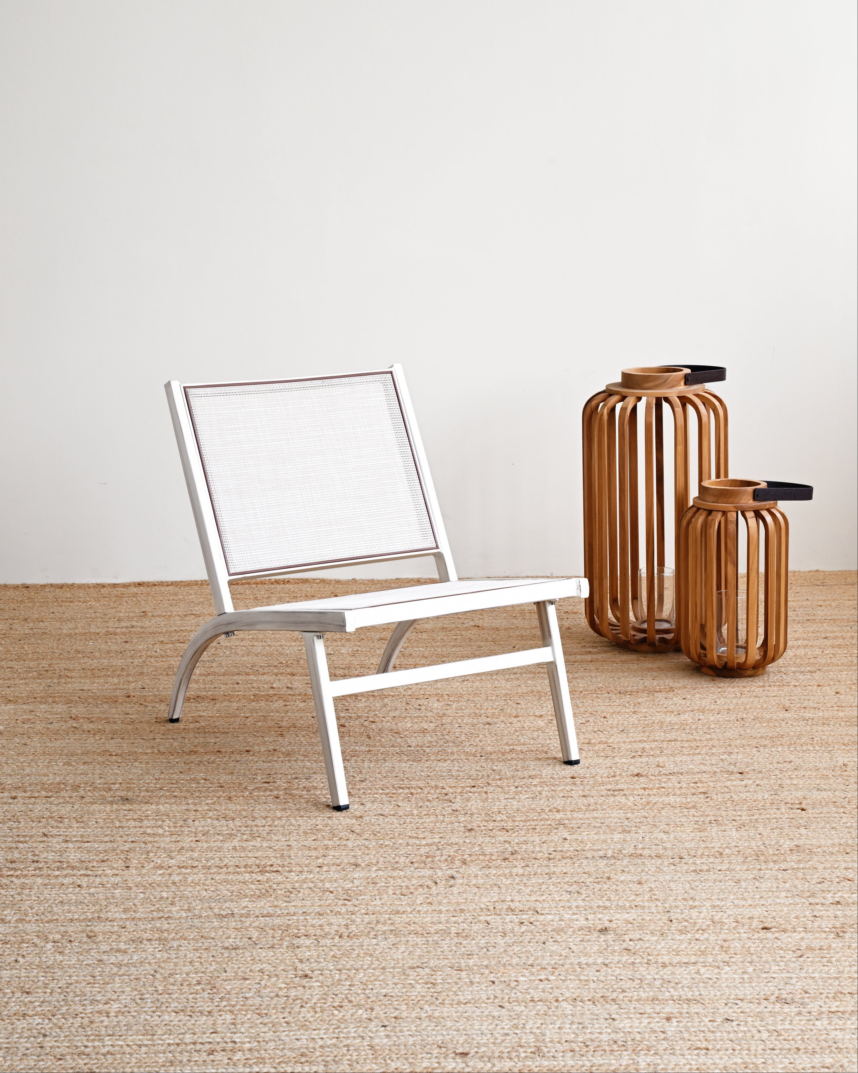 White chair on a textured floor with two wooden vases against a white wall