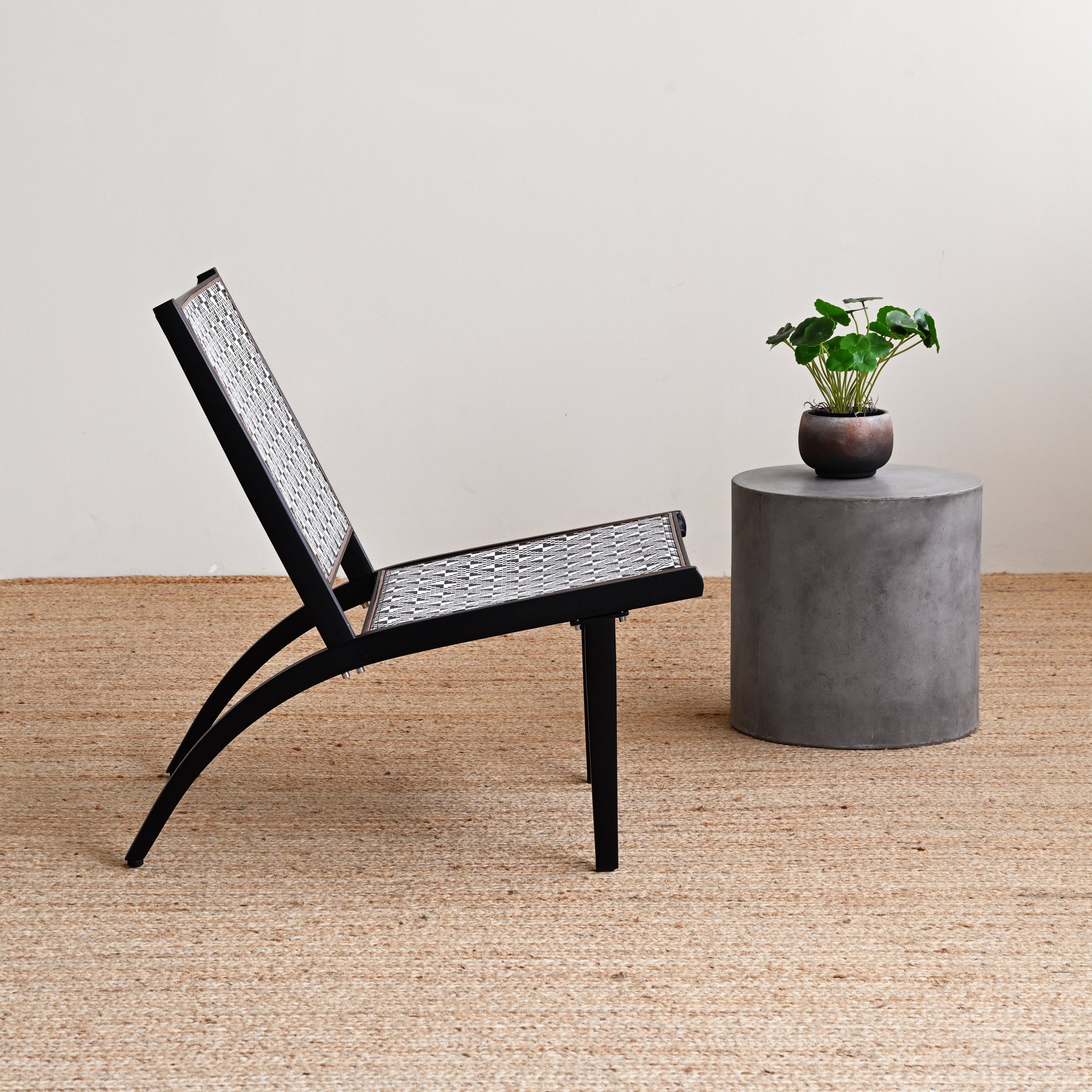 Black chair and concrete table with plant on a wooden floor
