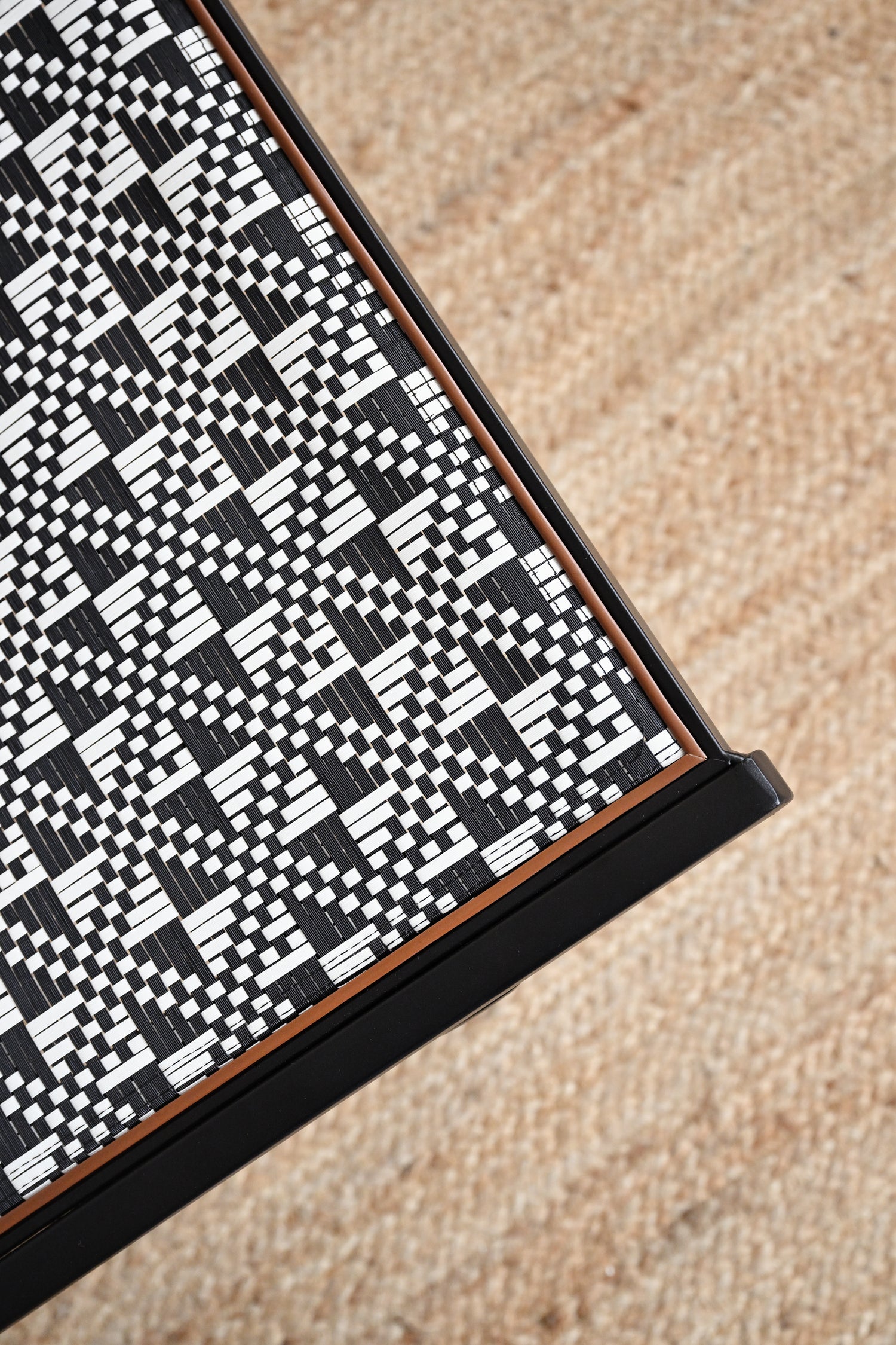 Close-up of a black and white geometric patterned rug on a beige carpet.