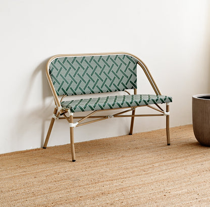 Rattan chair with green patterned cushion on a wooden floor against a white wall