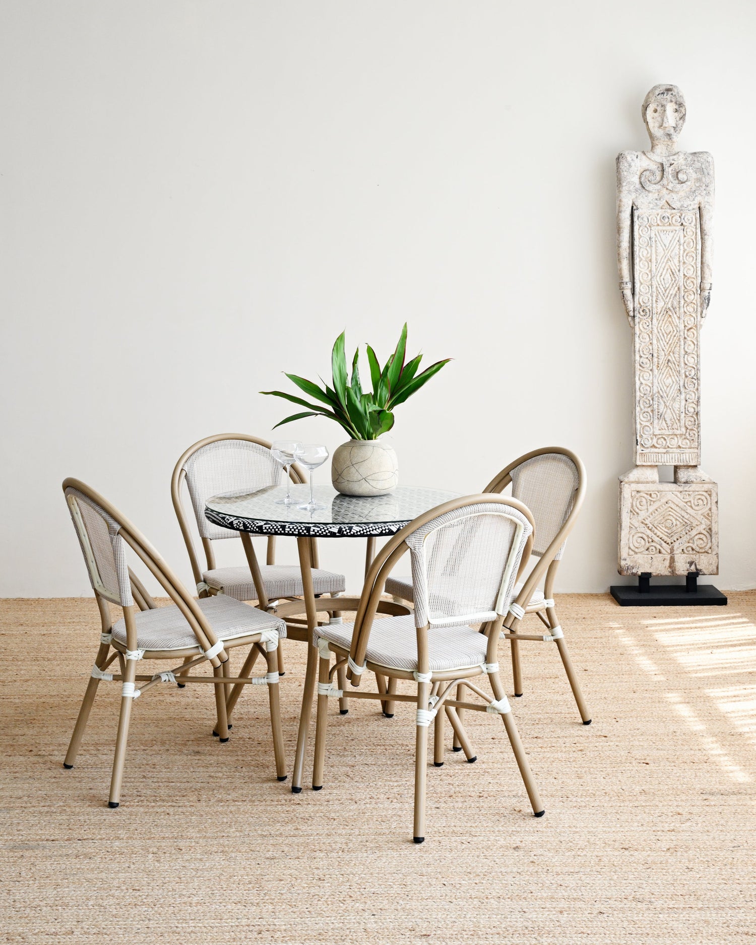 Dining area with round table and chairs in a room with a statue and plant.