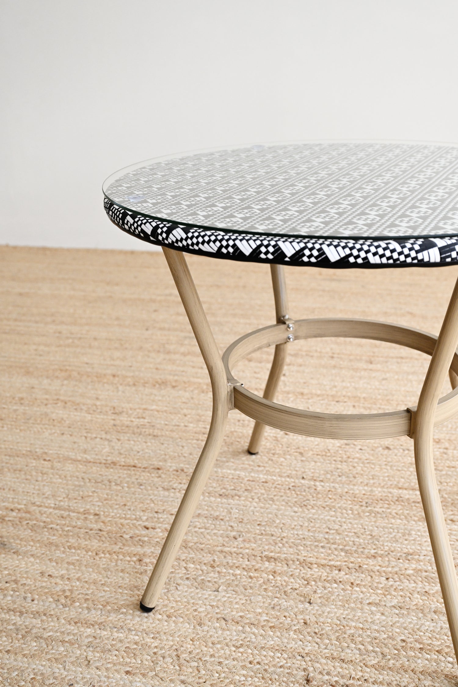 Round metal table with a decorative black and white rim on a beige floor.