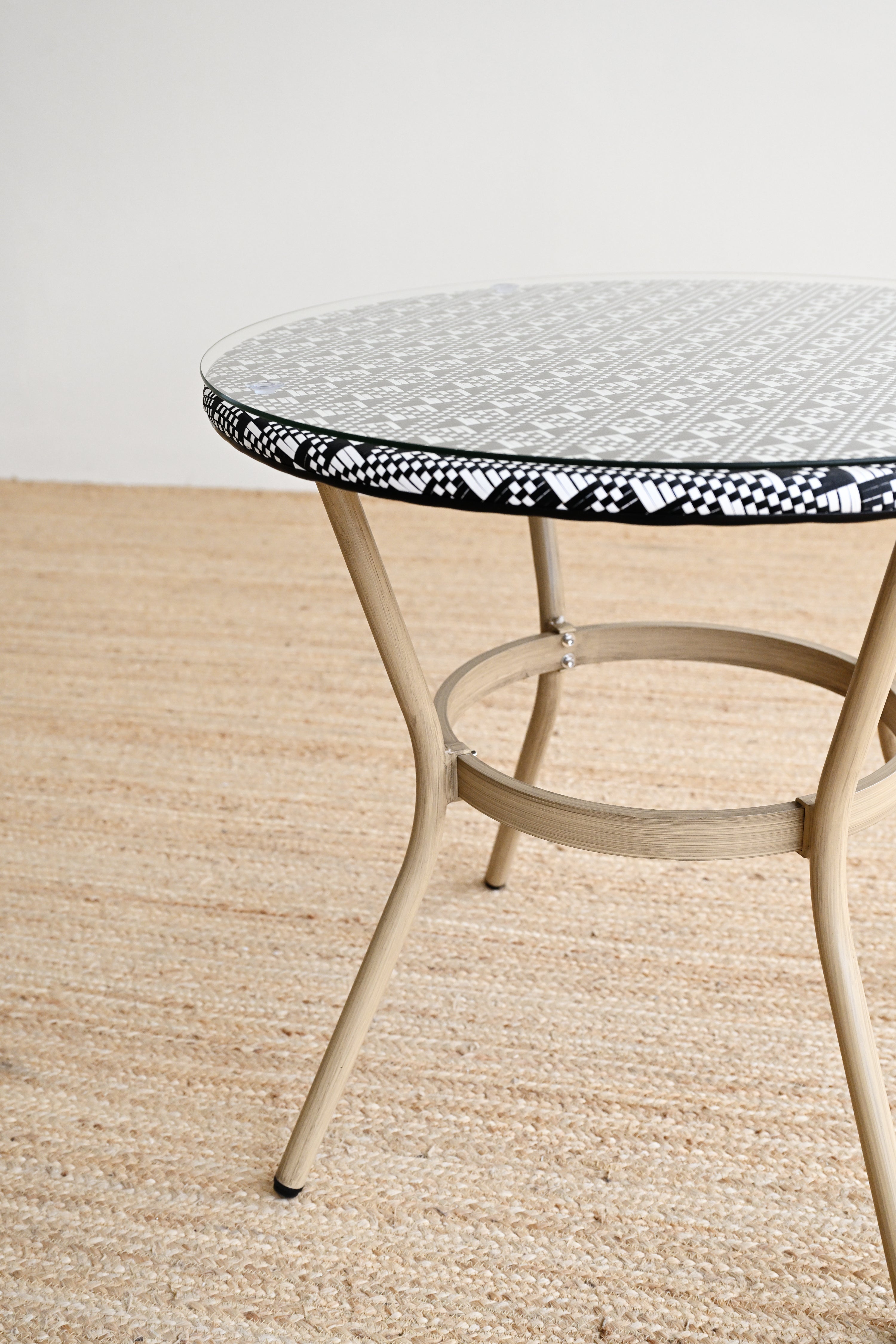 Round metal table with a decorative black and white rim on a beige floor.