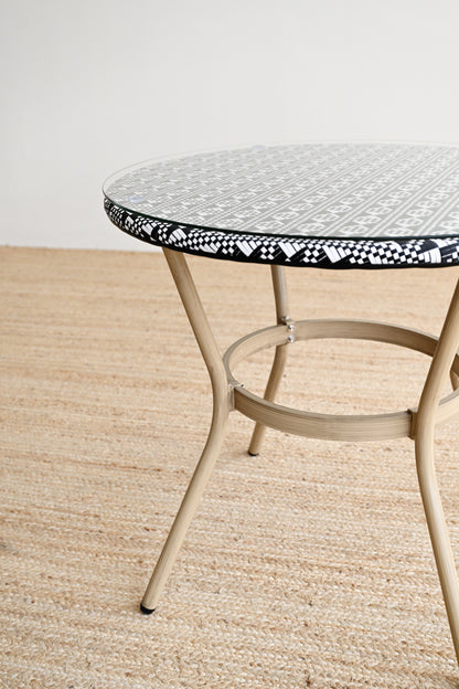 Round metal table with a decorative black and white rim on a beige floor.