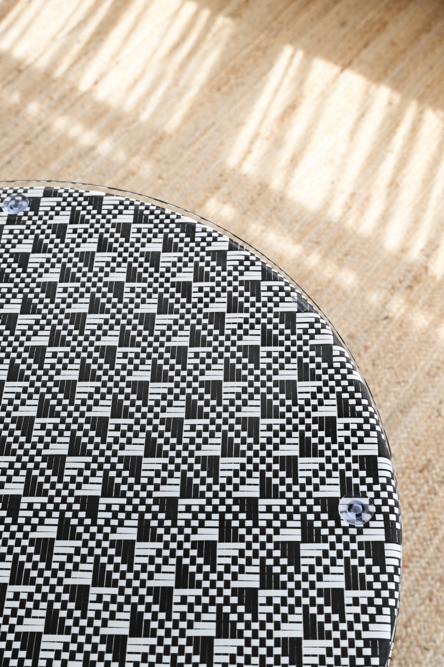 Round table with a black and white geometric pattern on a wooden floor.