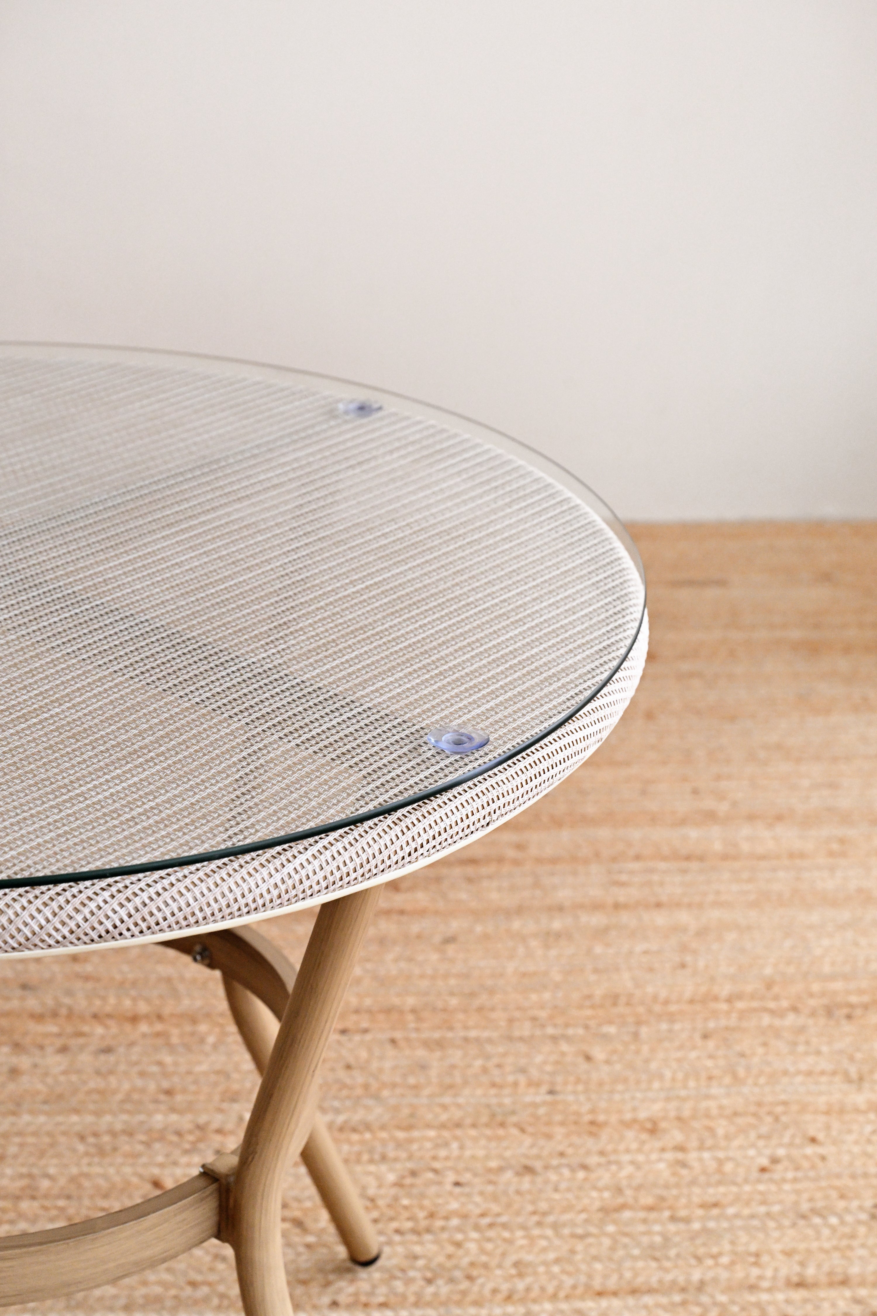 Round glass table with woven edge on a wooden floor