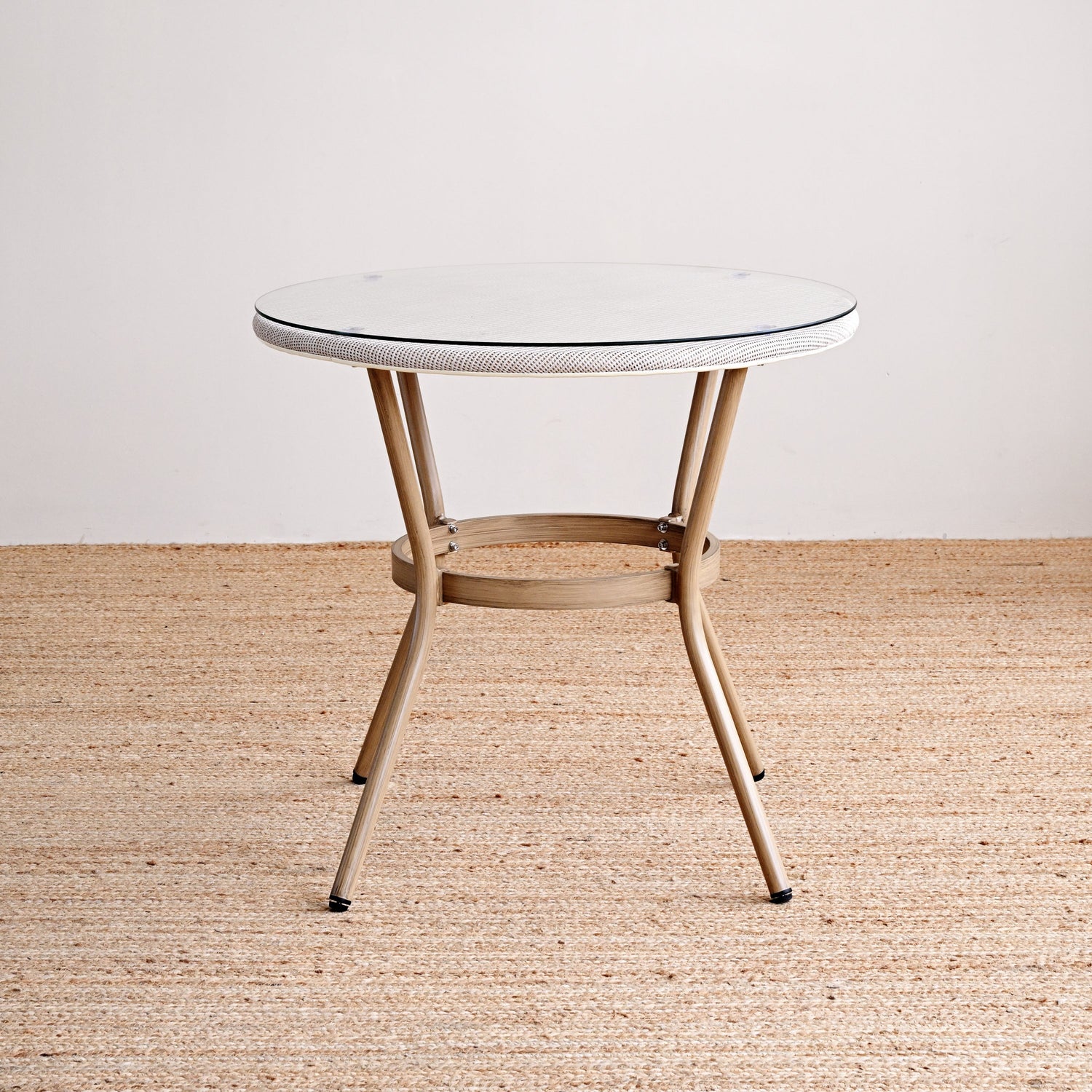 Small round table with a white top and wooden legs on a beige carpet.