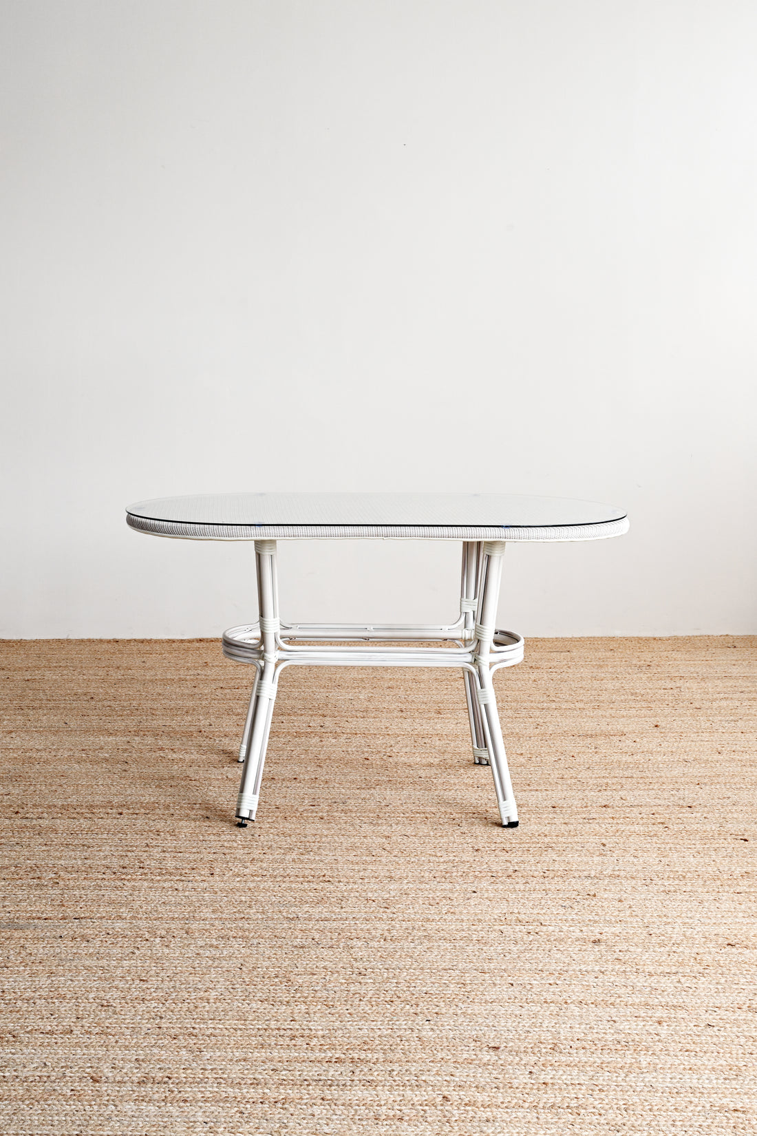 Round glass table with metal legs on a beige carpeted floor.