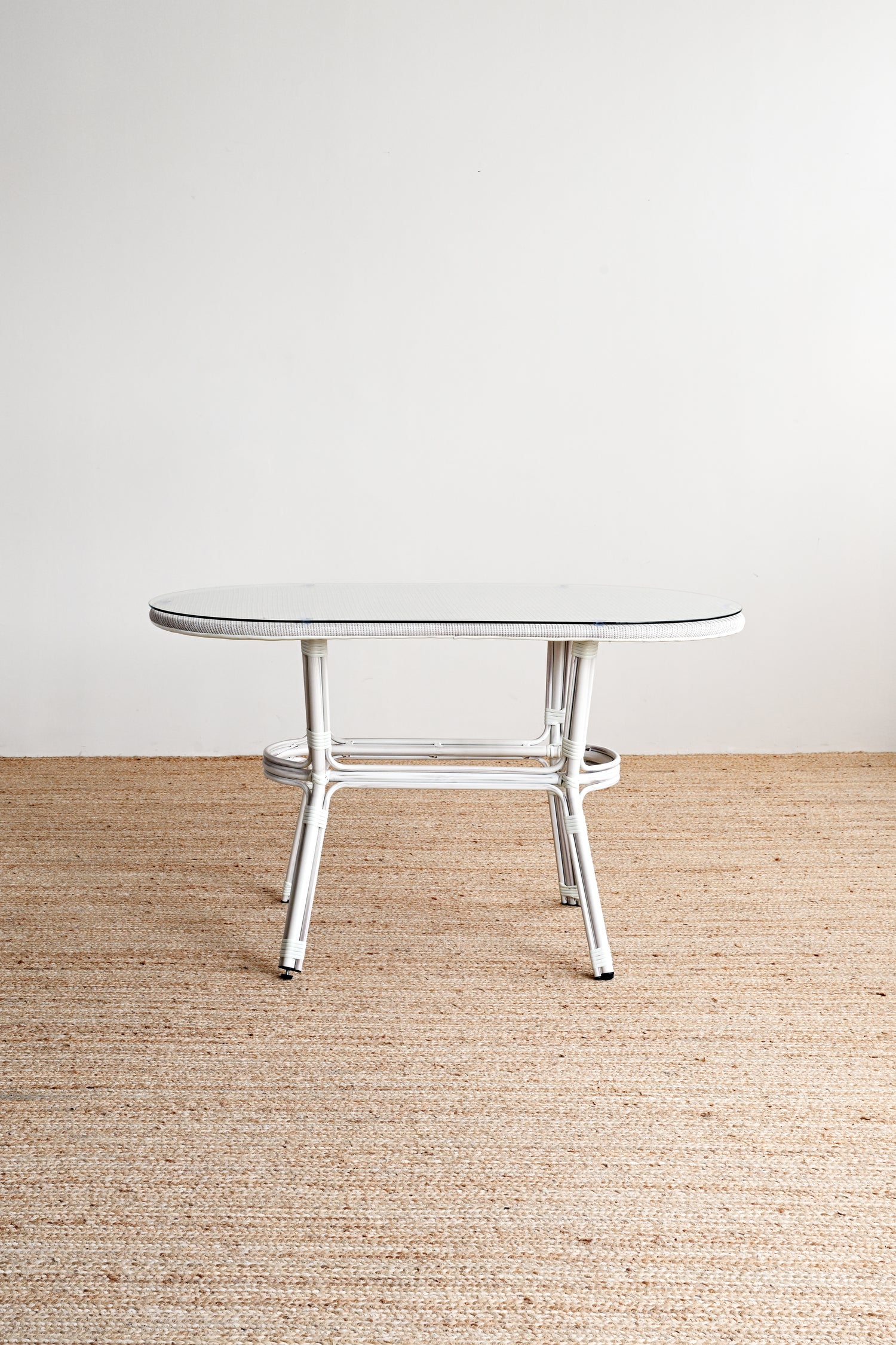 Round glass table with metal legs on a beige carpeted floor.
