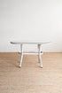 Round glass table with metal legs on a beige carpeted floor.