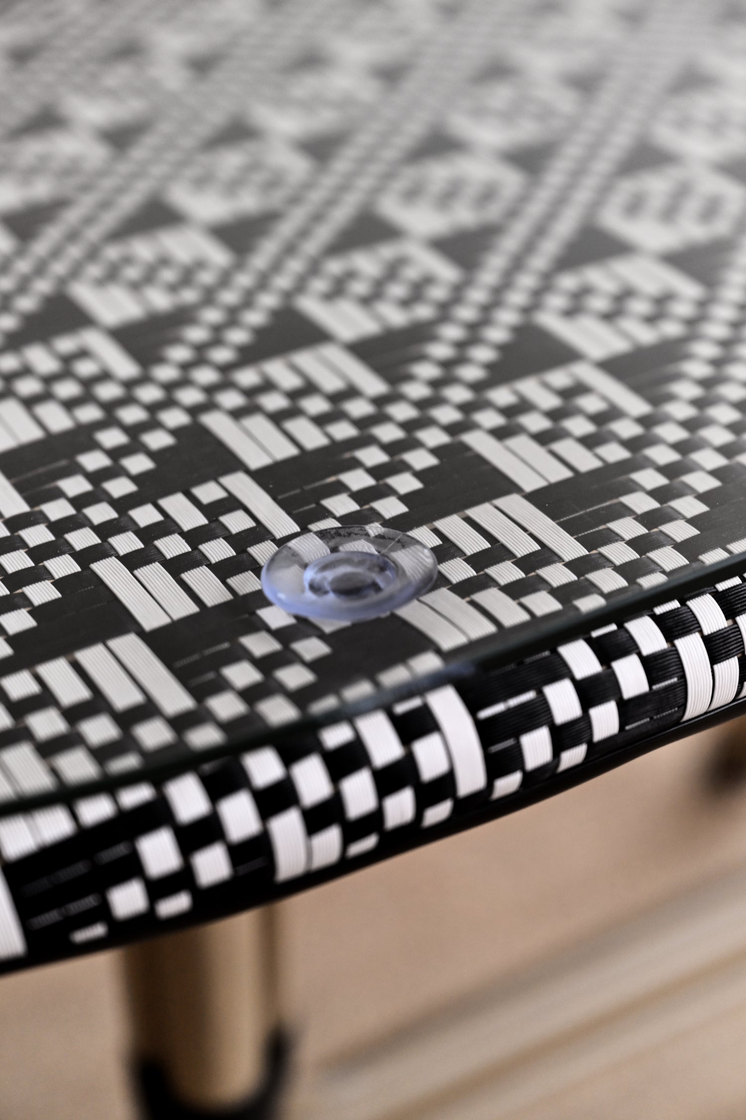 Close-up of a black and white patterned table surface with a clear plastic knob.