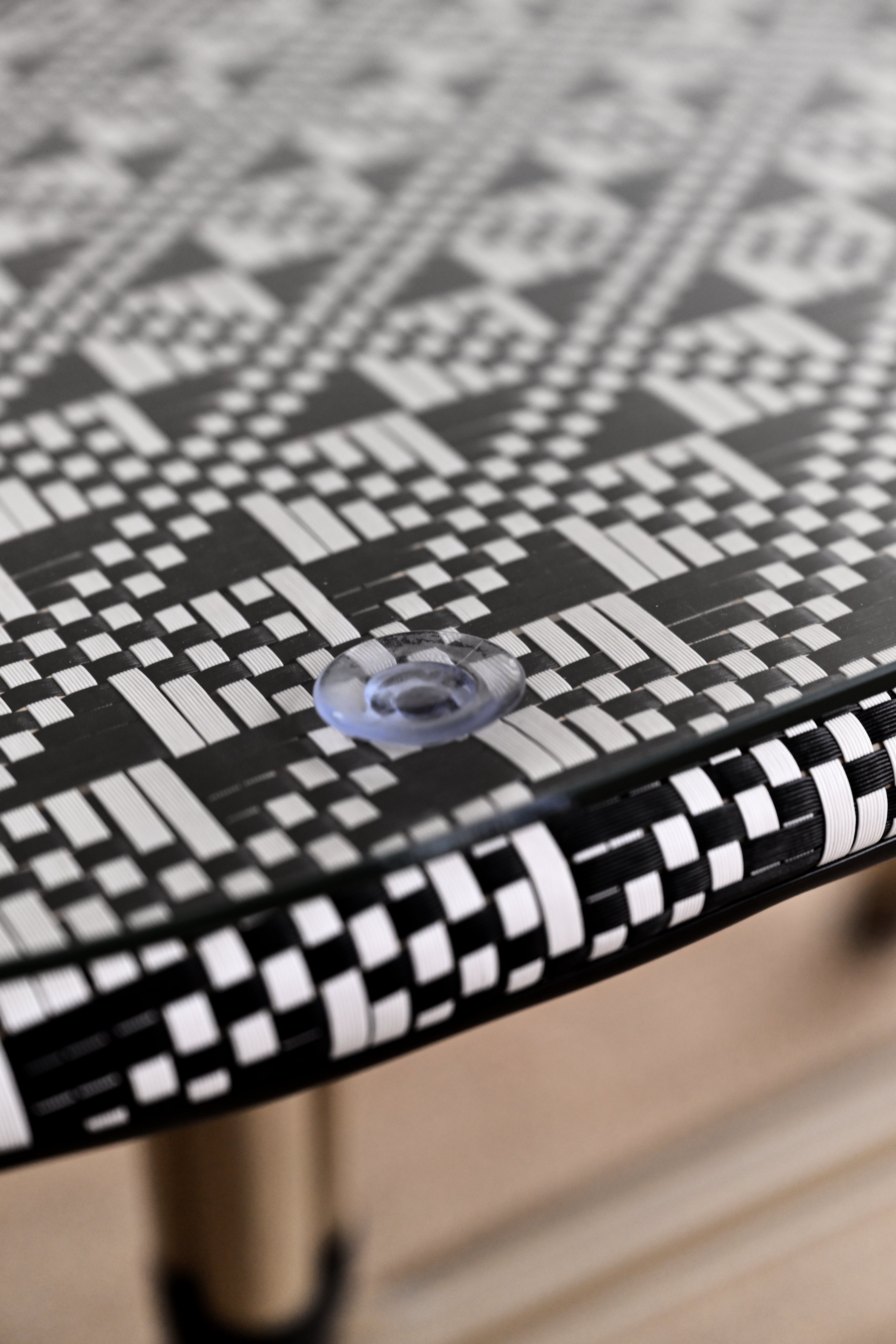 Close-up of a black and white patterned table surface with a clear plastic knob.