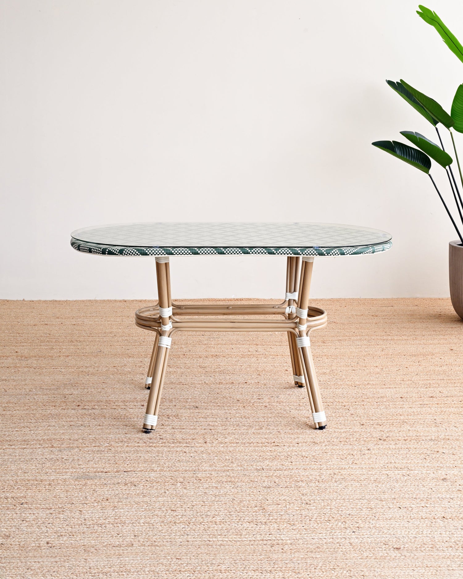 Round marble table with gold legs on a beige rug, plant in the corner.
