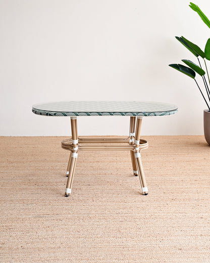 Round marble table with gold legs on a beige rug, plant in the corner.