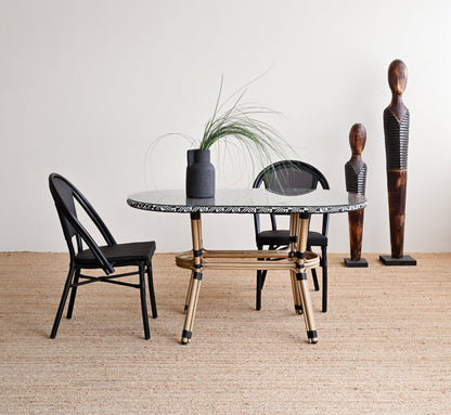 Dining area with a marble table, black chairs, and decorative vases against a white wall.