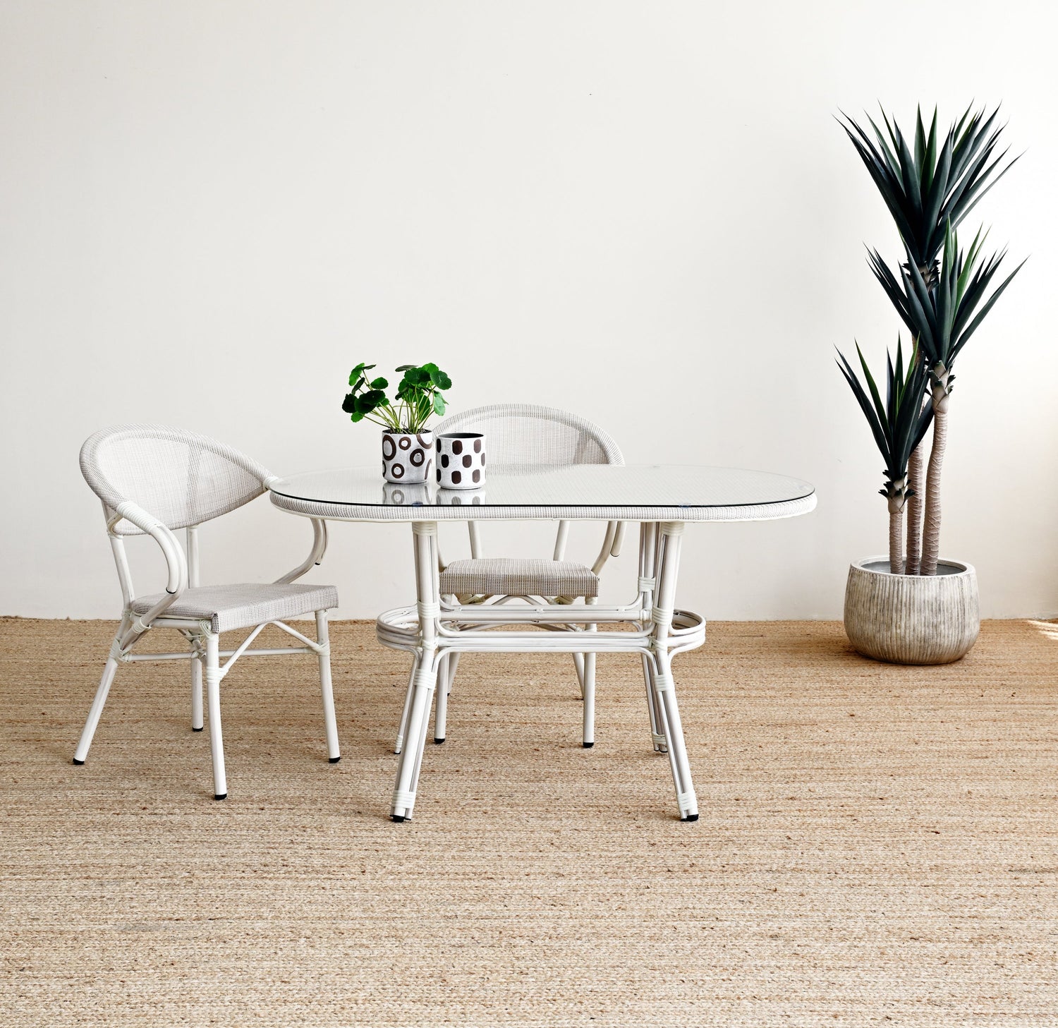 Dining area with a round glass table and two chairs on a textured beige floor.