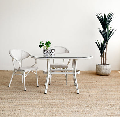 Dining area with a round glass table and two chairs on a textured beige floor.