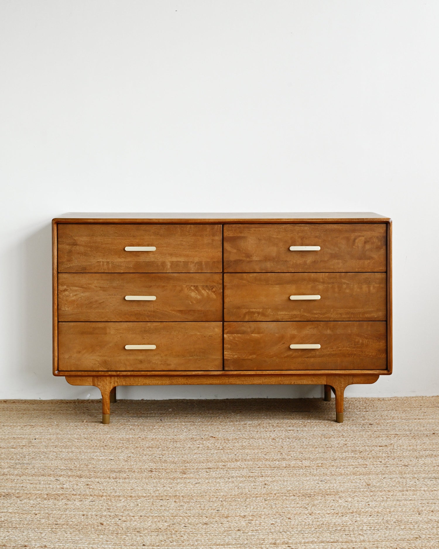 Wooden dresser with six drawers on a beige carpet against a white wall