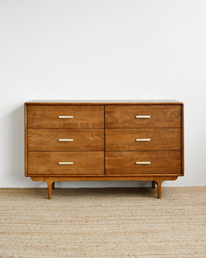 Wooden dresser with six drawers on a beige carpet against a white wall