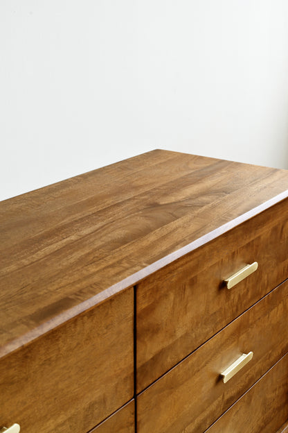 Wooden dresser with gold handles on a white background