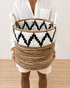 Person holding a woven basket with geometric pattern