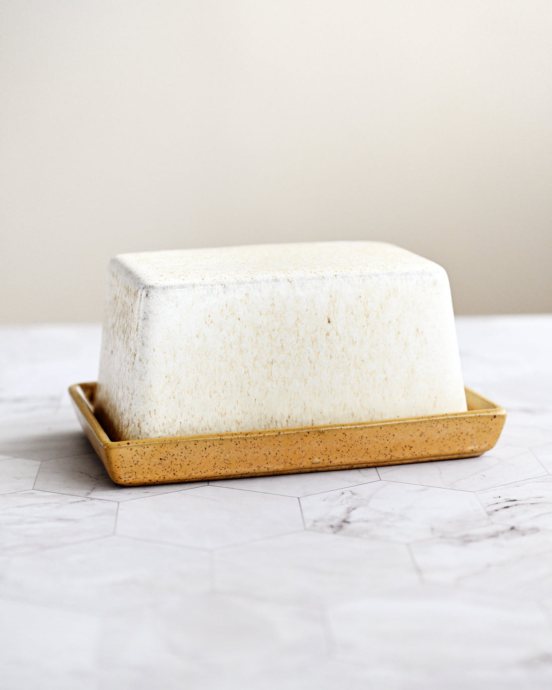 Block of butter on a wooden tray with a marble surface and light background
