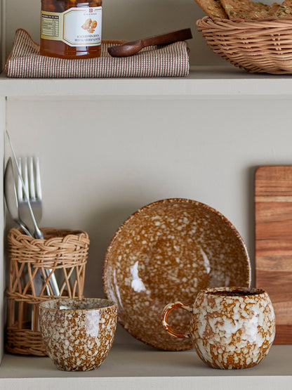 Ceramic dishes and utensils on a shelf with a neutral background