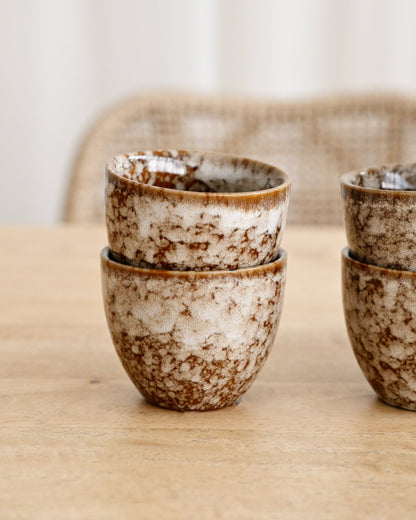 Stacked ceramic bowls with speckled pattern on a wooden surface
