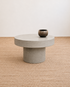 Concrete coffee table with a vase on a textured beige floor and white wall