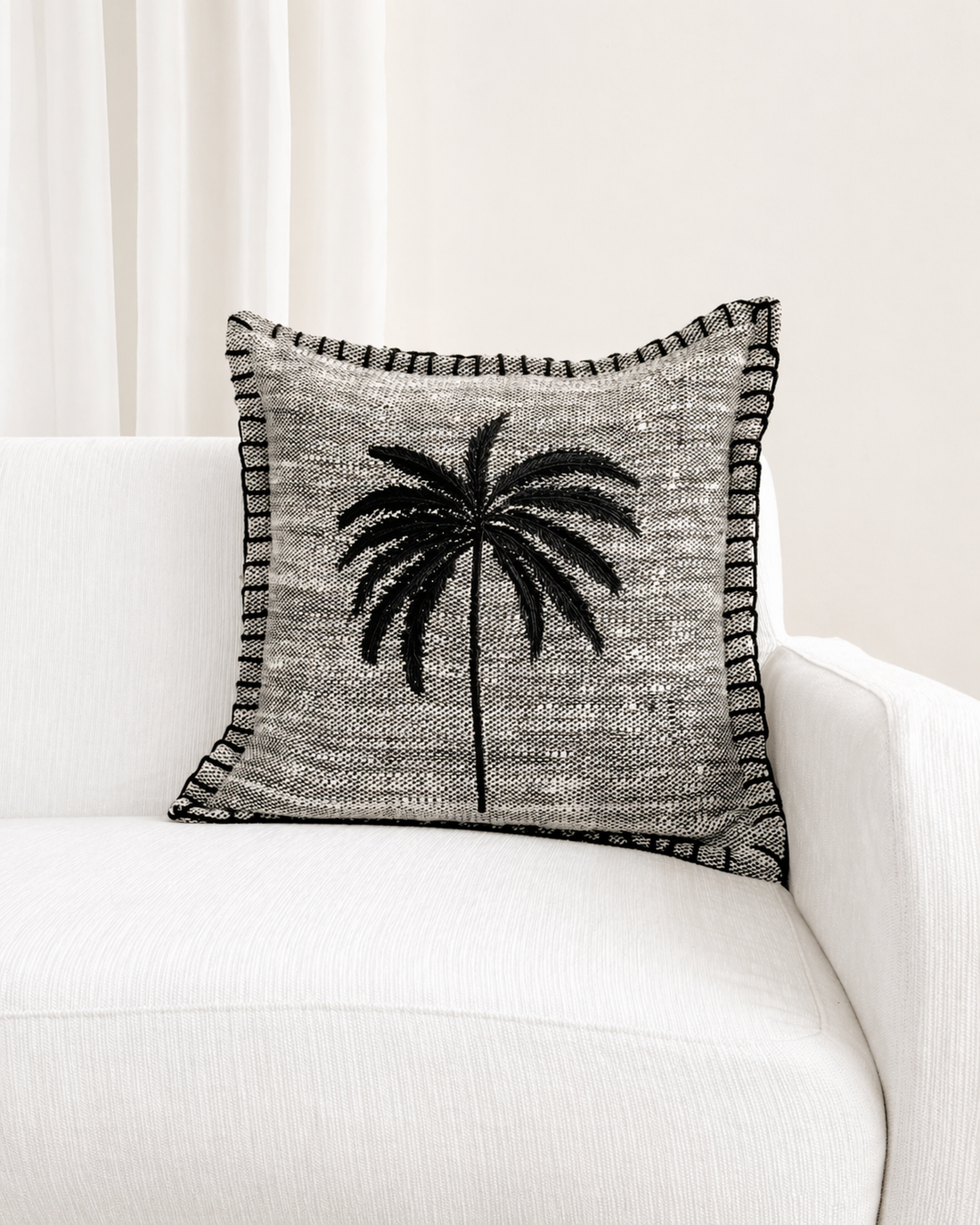 Decorative pillow with palm tree design on a white couch