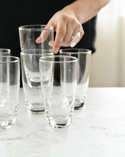 Clear glasses on a marble surface with a hand reaching in.